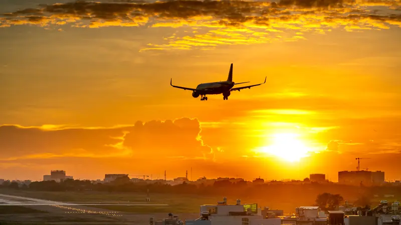 Passenger plane coming in to land at sunset over a city in Vietnam